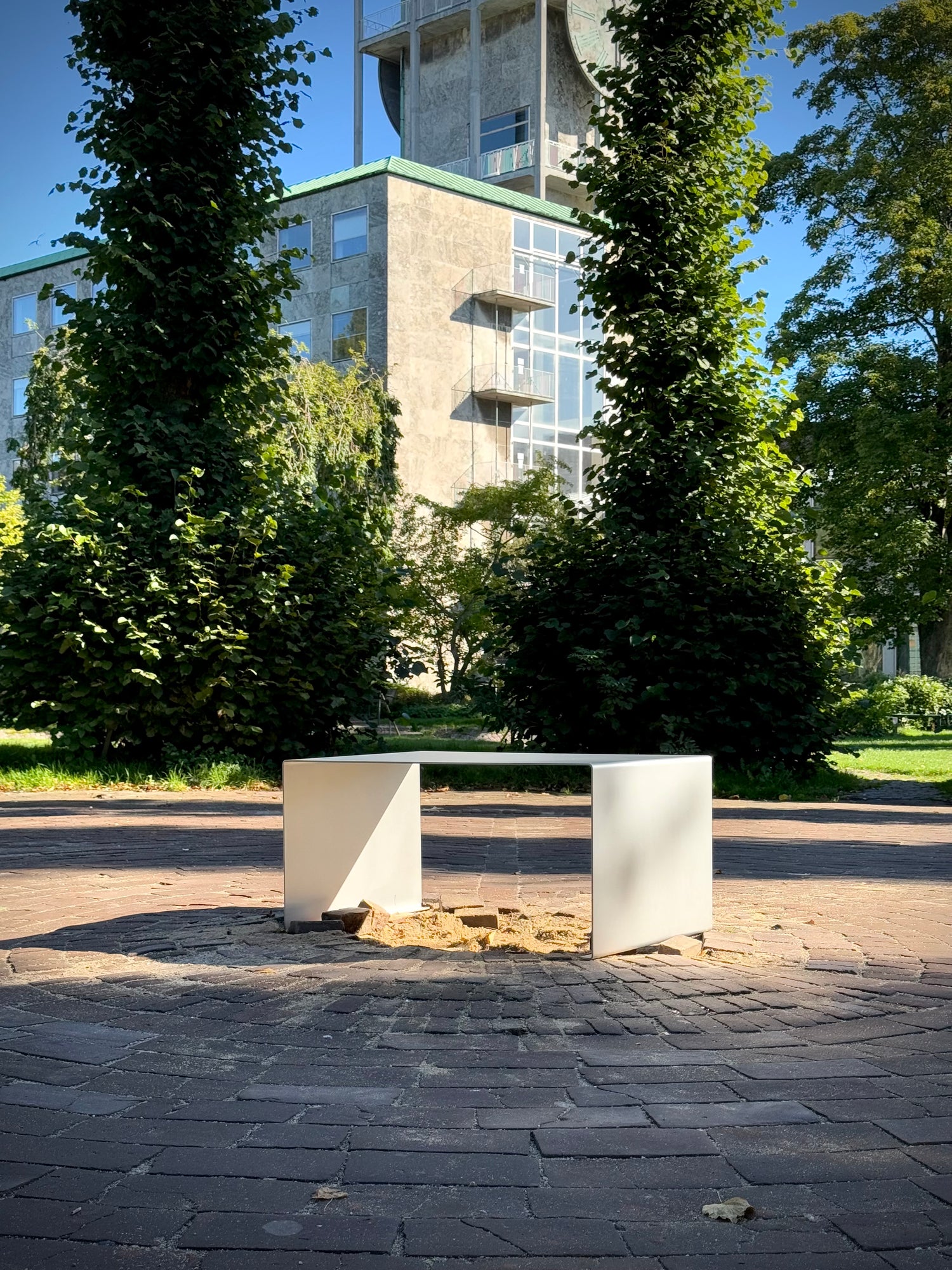 Stainless steel furniture by Bendix Angarde photographed in front of Aarhus City Hall, designed by Arne Jacobsen — a dialogue between modern design and architectural heritage.