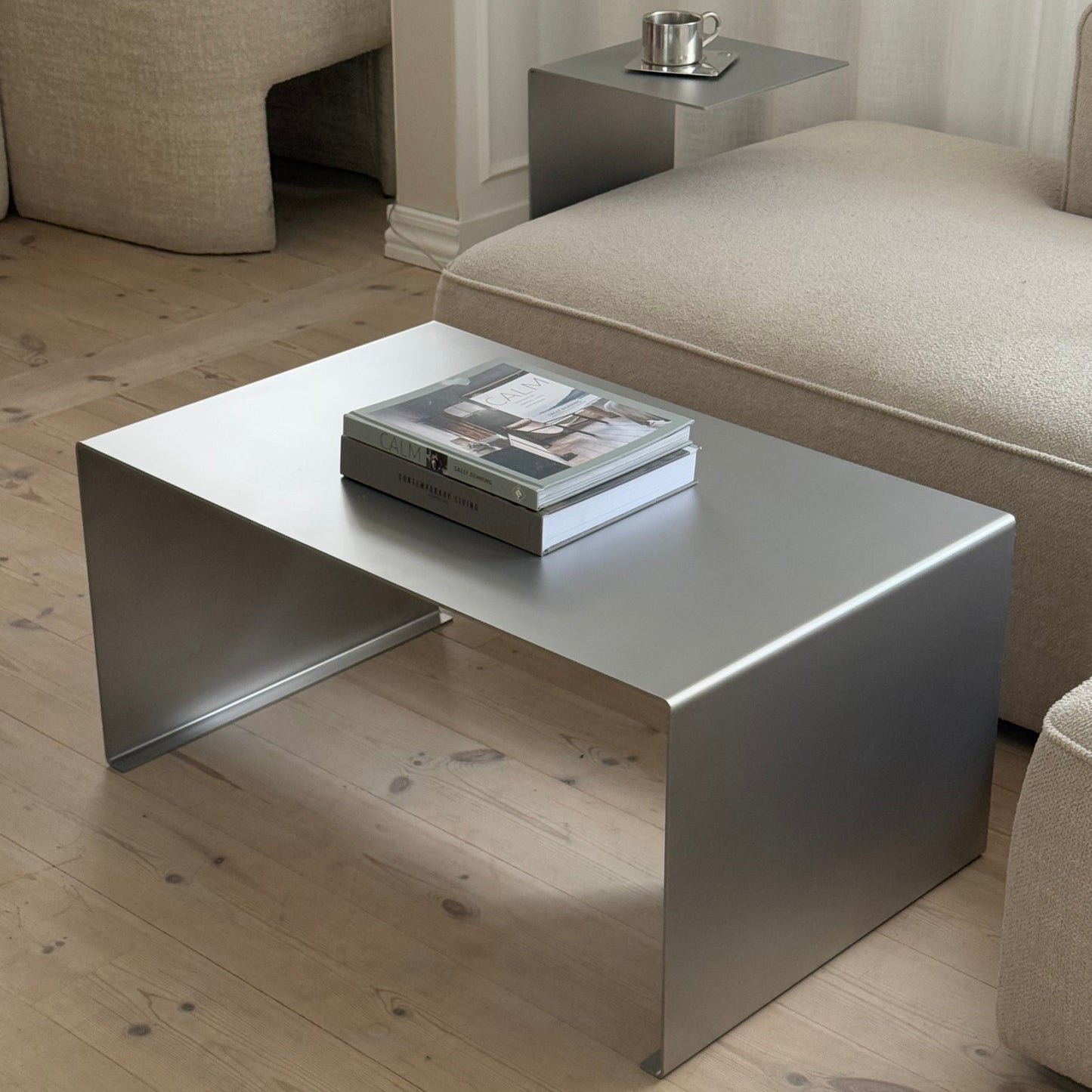 Elegance Coffee Table in stainless steel with satin-matte finish, placed in a modern living room.