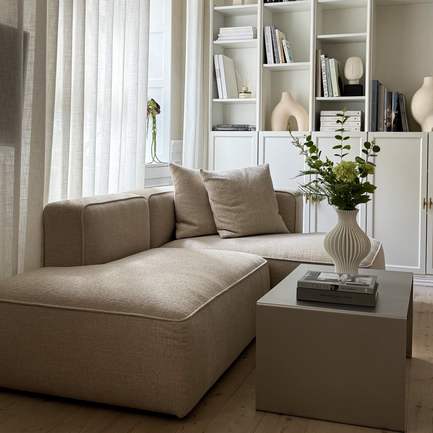 Side view of the Elegance Coffee Table with a vase and shelf in the background.