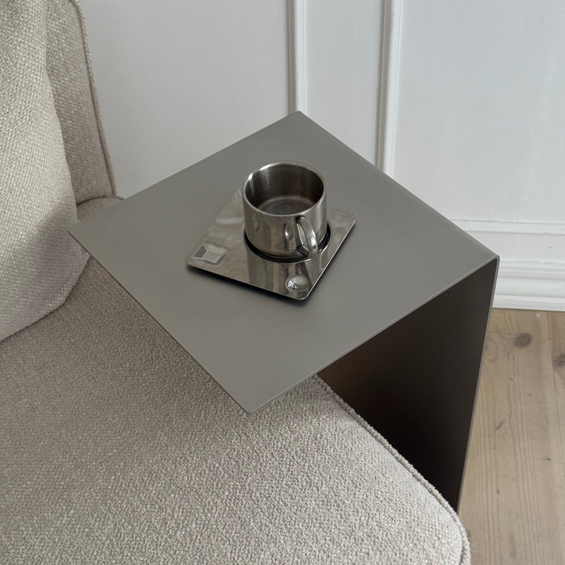 Angled front view of the Elegance Side Table beside an armchair in a soft-lit room.