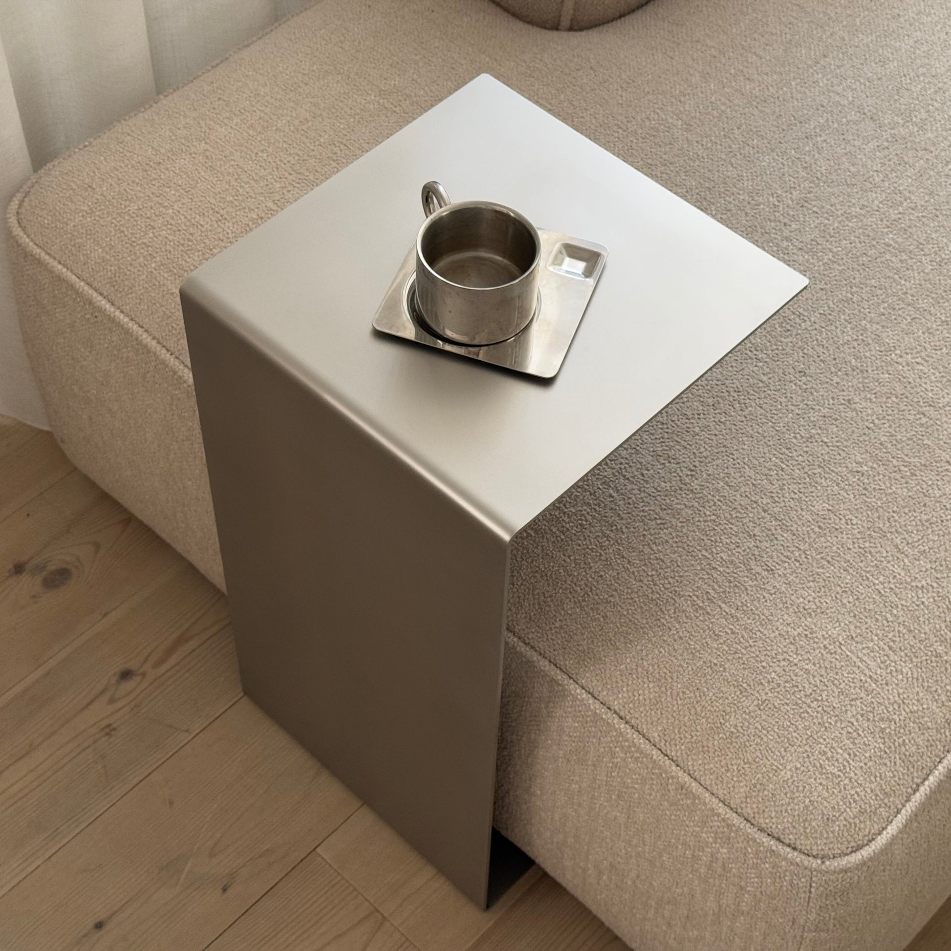 Angled top view of the Elegance Side Table next to a sofa, seen from the right side.