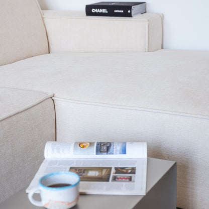Angled view of the Elegance Side Table in reversed orientation with magazines and coffee cup.
